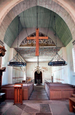 Church interior with two large chandeliers either side of aisle above pews