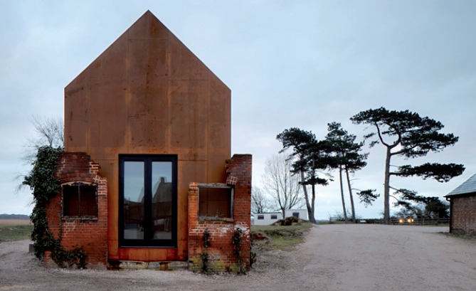 A Corten steel building cloaked in the roofless ruin of a brick Victorian structure at Snape Maltings