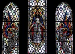 Three-light window with the ascension of Christ depicted in the central light and angels looking on from the outer lights
