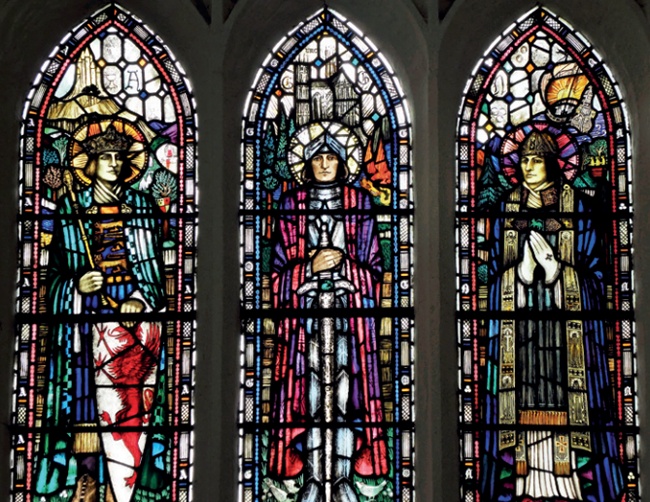 Intensely decorated and richly coloured three-light window with King Arthur occupying the central light; he holds his sword point downwards in front of him