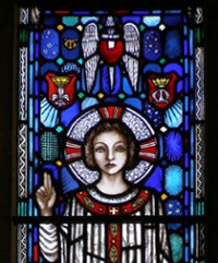Detail of the blue window depicting haloed figure with hand raised in benediction