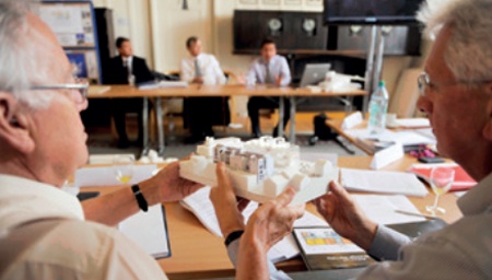 Members of a competition jury pass around an architect's model