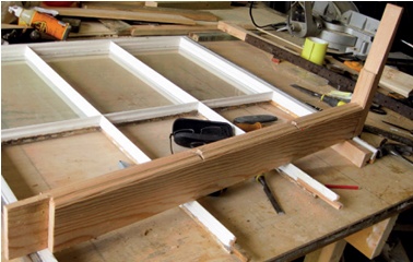 Window sash on workbench with new stile stood upright on top of it prior to fitting