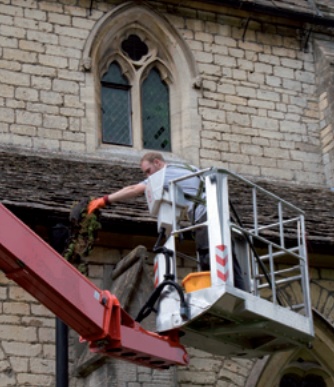 Man clearing gutter from cherry-picker platform