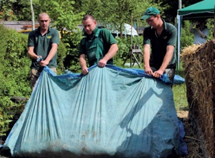 Three men turn the mix using a tarpaulin