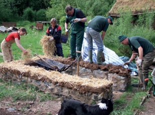 Straw is spread over the clay which has been levelled out on top of the low masonry plinth