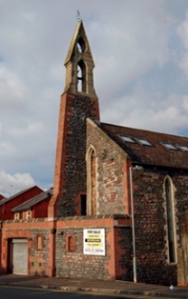 The exterior of All Saints, Adamsdown which incoporates a beautiful patchwork of stone and brick and a slender bellcote structure embedded like a blade in the church's west west elevation