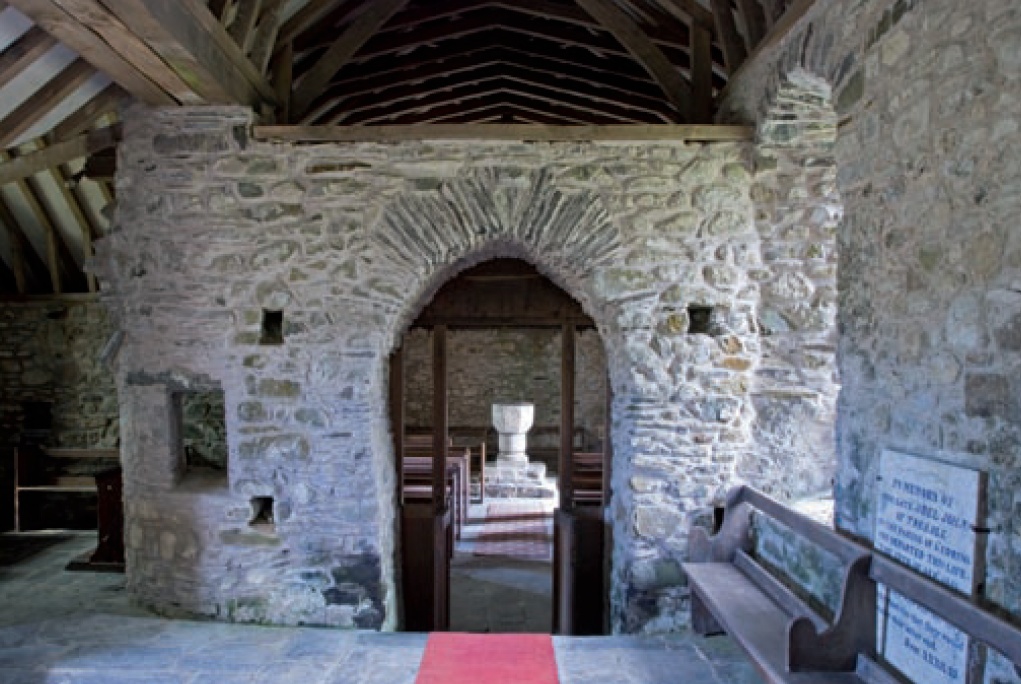 Font seen through stone archway at St Teilo, Llandeloy