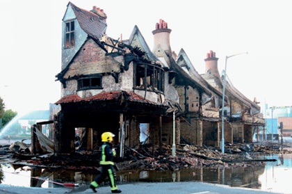 A firefighter walks past a burnt-out historic building