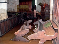 Pews surrounded by receding brown floodwater
