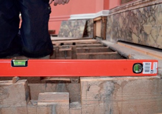 A spirit level laid along a joist shows the gallery floor sloping towards its outer edge