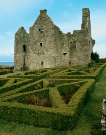 The ruins of Tully Castle with symmetrical box hedge planting in the foreground