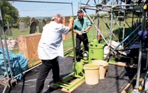 Two men operating a pump at the foot of the scaffolding