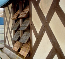 The restored belfry: the window opening shown is formed of two lancets and has four pairs of shingle-clad louvres