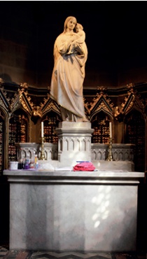 Well-illuminated statue of Madonna and child on marble altar