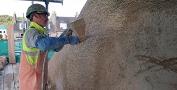 Harling being applied using a hose-fed, mechanical spray system