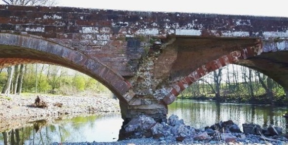 Badly damaged masonry bridge with collapsed spandrel