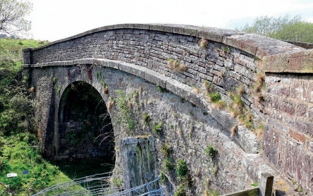 Railway bridge with much missing pointing and weeds growing from the gaps