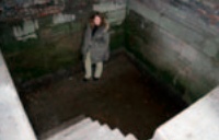 Photograph of woman standing in empty plunge bath and looking up at camera