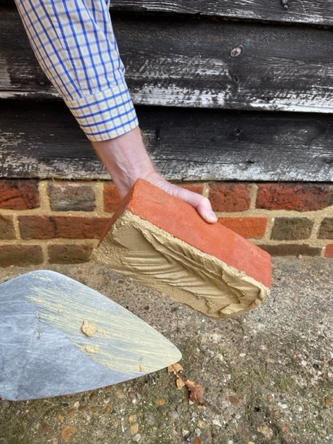Mortar being liberally applied to the underside of a brick