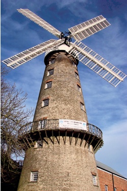Restored windmill with brick facade and timber walkway or 'reefing stage' at third-floor level