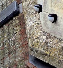Pair of small plastic movement dectectors fixed to historic masonry wall