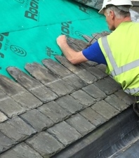 Roofer nailing slates with rounded upper edges