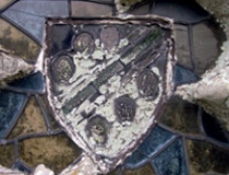 Stained glass window depicting an armorial device with pale green lichen growth