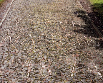 Lettering built into a cobble path using paler stone. The date 1874 is legible in the foreground.