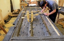 A conservator repairs an oak door in the workshop
