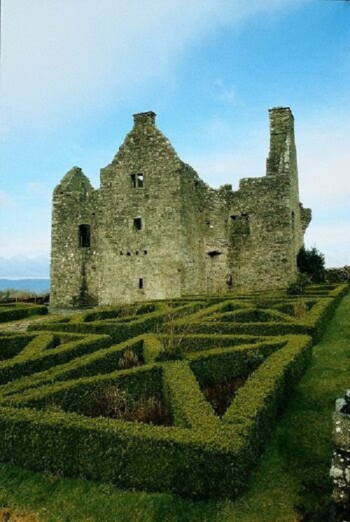 The ruins of Tully Castle with symmetrical box hedge planting in the foreground