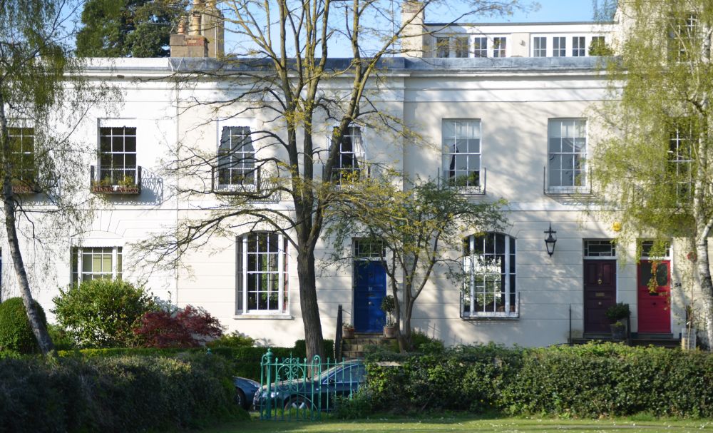 Georgian stucco terraced houses seen from across a lush green space