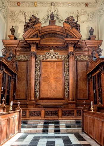 Intricate limewood carvings surround the darker central panel of the reredos