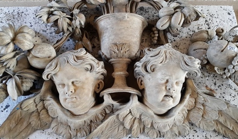 Limewood cherub heads with wings, urn and carved vegetation