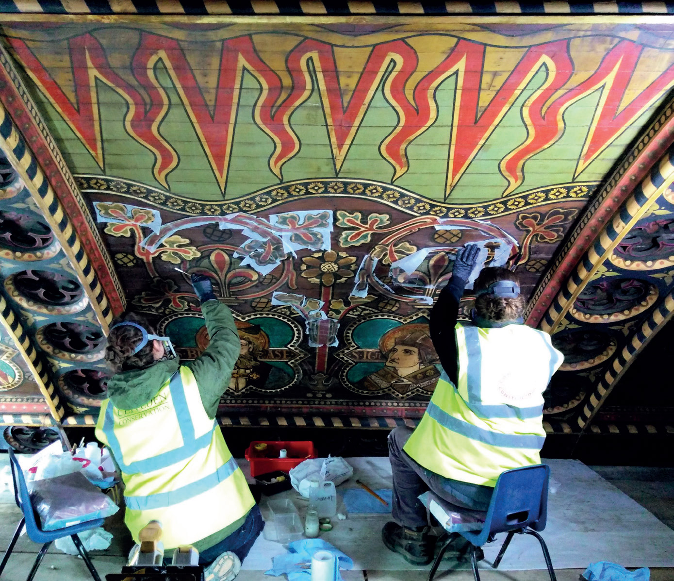 Conservators removing the darkened layers of varnish from the nave ceiling panels