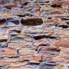 Badly eroded masonry behind a matrix of largely intact cement mortar