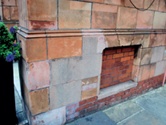 Discoloured mortar repairs to mixed brick and terracotta wall. The mortar repairs have bleached to a pale grey and stand out from the sandy colour of the original terracotta