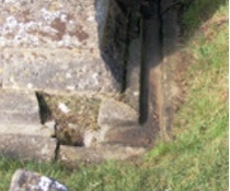 Broken stone channel for rainwater run-off at base of masonry wall