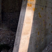 Repaired section of a concrete buttress which looks paler and cleaner than the surrounding original concrete