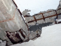 Exposed, corroded grid of reinforcement bars embedded in damaged concrete floor slab