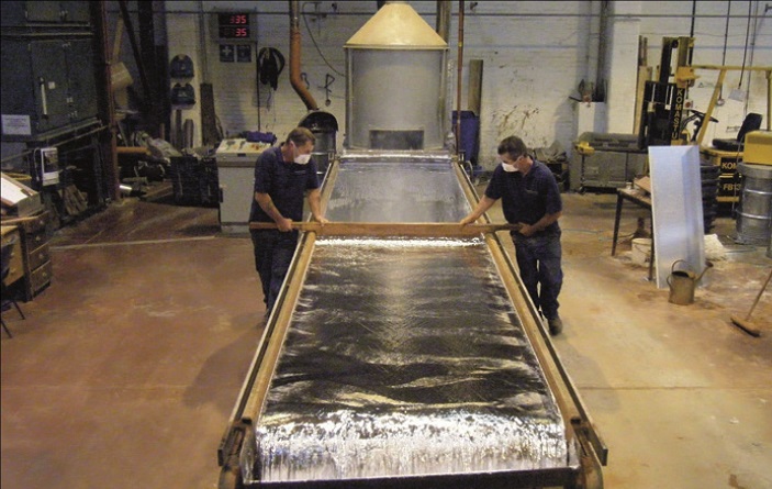 Sand-cast lead still created using the same process, with workers wearing protective equipment