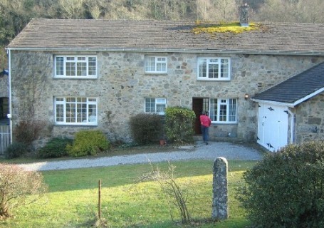 Large, two-storey dwelling with large window openings and unrendered stone walls