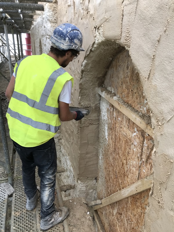 A lime render being applied to a masonry wall