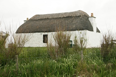 A cottage on Benbecula which had a marram thatched roof secured with ropes and modern bricks as weights