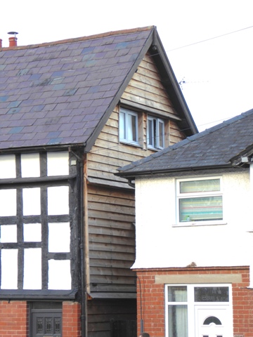 Weatherboarded gable end close to neighbouring property; angled pentice boards have been fitted at three levels to improve shedding of rainwater