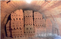 Bricks stacked high for firing in a tunnel-shaped kiln chamber