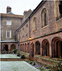Section of brick cloister surrounding frost-covered lawn 