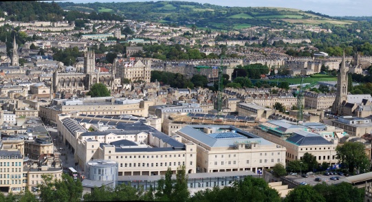 View of historic and modern buildings in central Bath with open countryside beyond